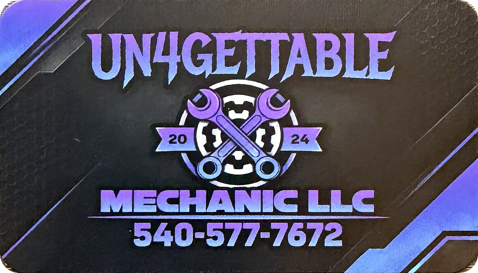 Printed UN4GETTABLE Mechanic LLC business card front with a purple and blue crossed-wrench and gear badge, a 2024 ribbon and phone number 540-577-7672